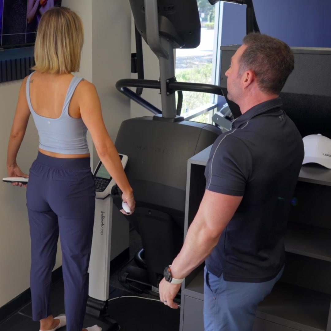 A client standing on the body composition scanner while Bryan Greene looks on