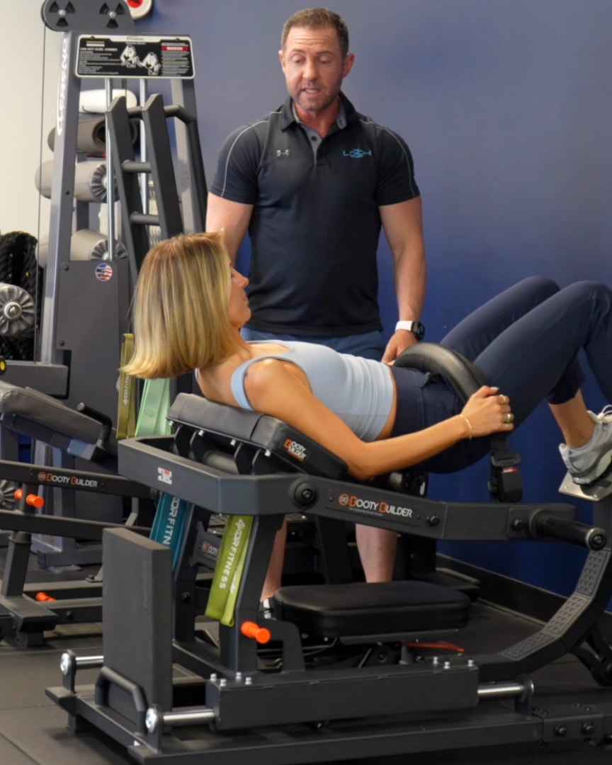 Bryan Greene coaching a client through a hip thrust on the glute machine
